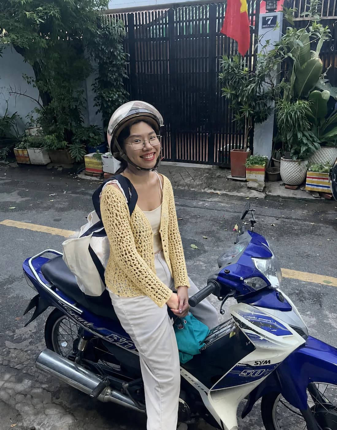 Butter yellow handmade crochet cardigan beside a scooter
