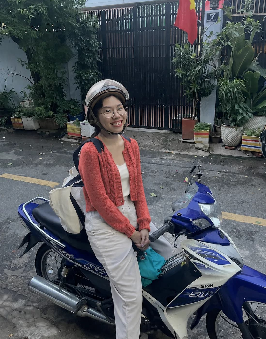 Coral cable-knit cardigan beside an antique scooter