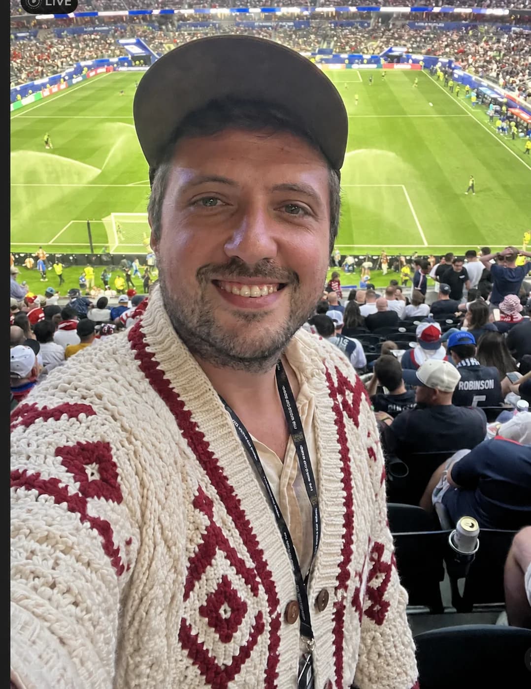 Classic ivory Aran cable cardigan at an outdoor stadium