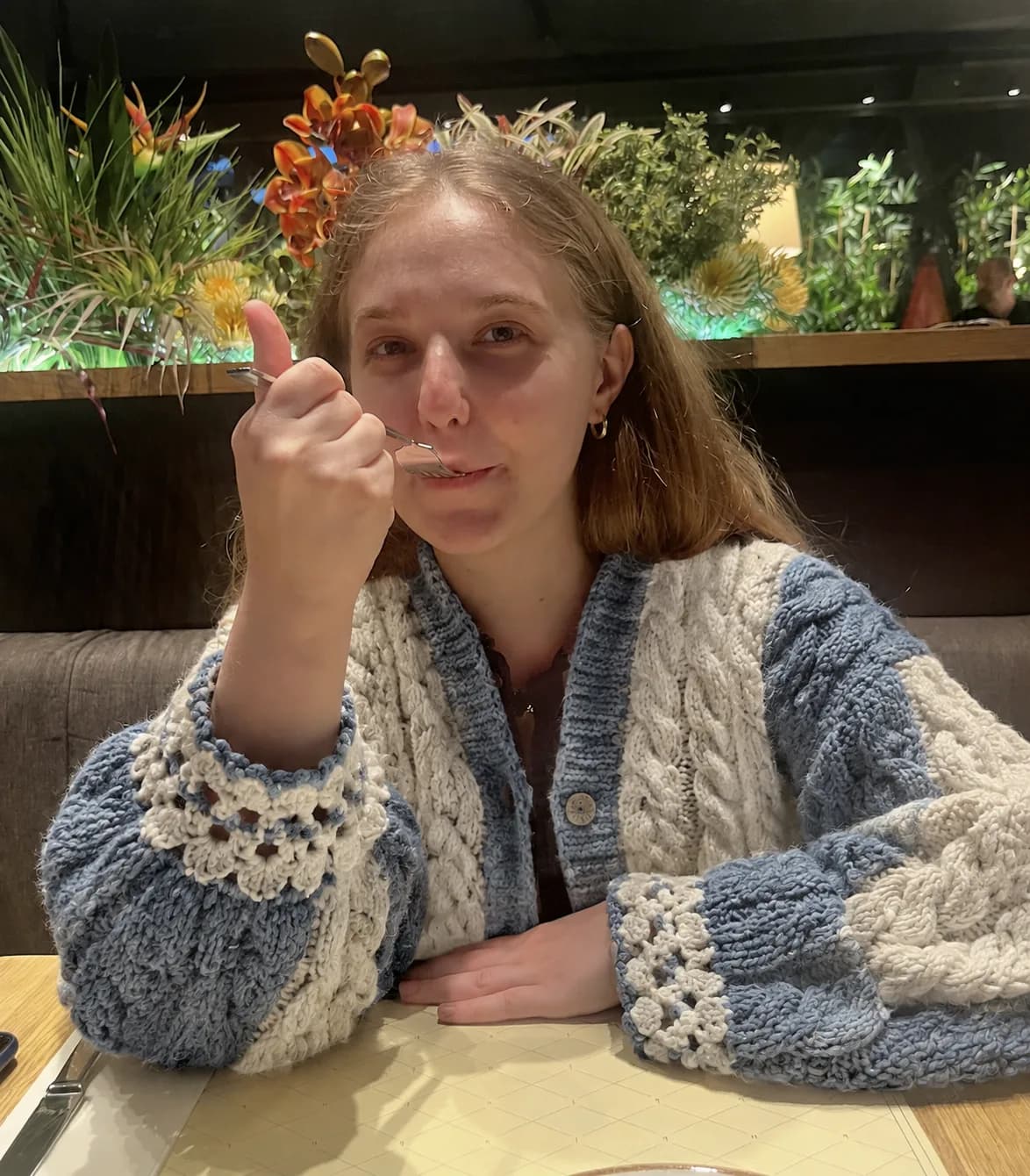 Cream and deep blue cable-knit cardigan in a cafe courtyard