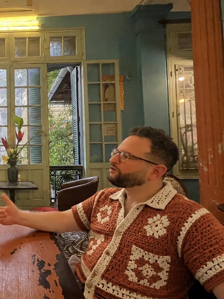Sunset-tone handmade amber crochet shirt on a man in an evening cafe
